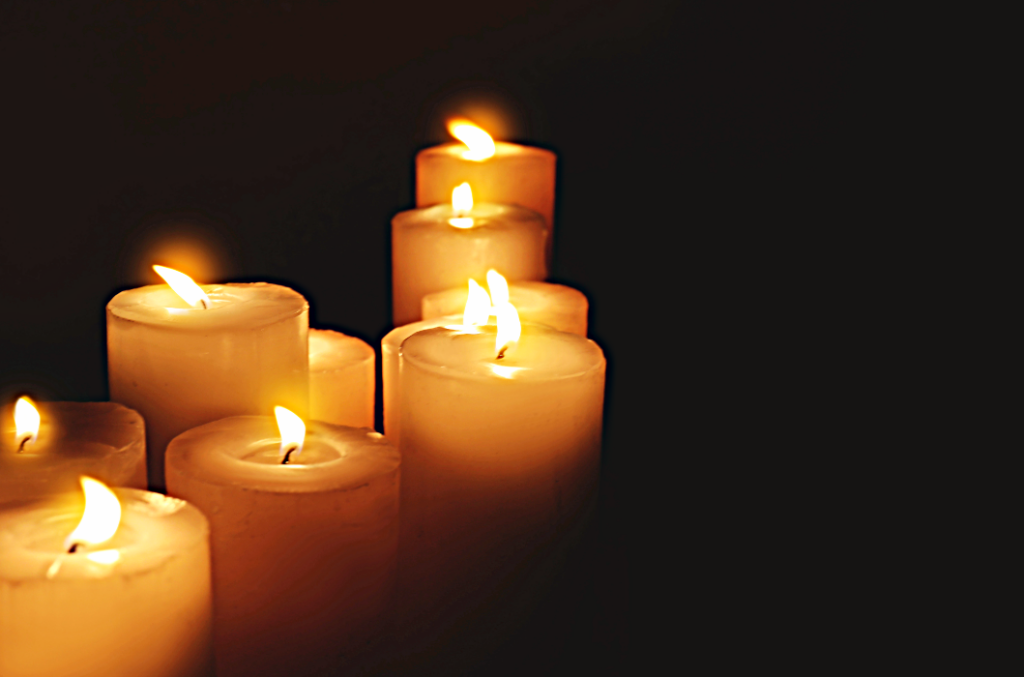 Lit memorial candles against a dark background